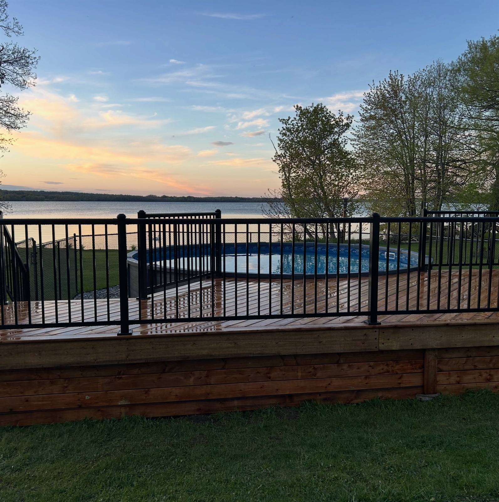 Lakeside deck with black aluminum railing at sunset, built by Gonzo Construction in the Kingston area