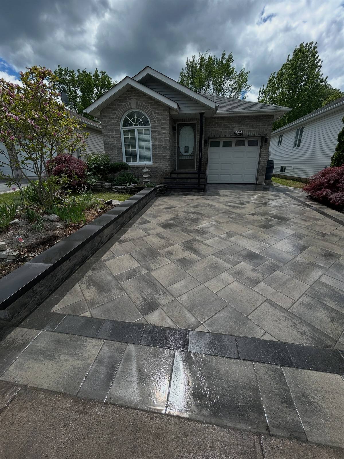 Interlock driveway with dark banded border at a brick bungalow in Kingston, Ontario