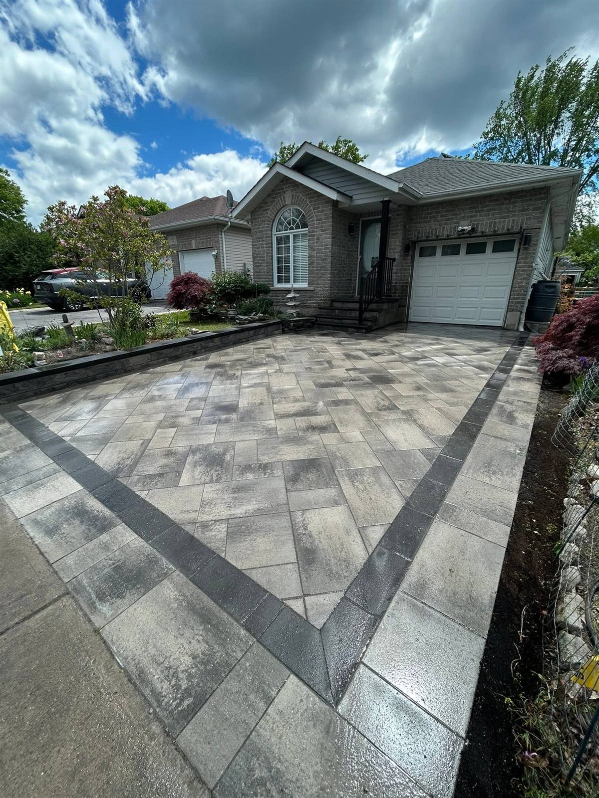 Interlock driveway with a charcoal soldier-course border installed by Gonzo Construction in Kingston, Ontario