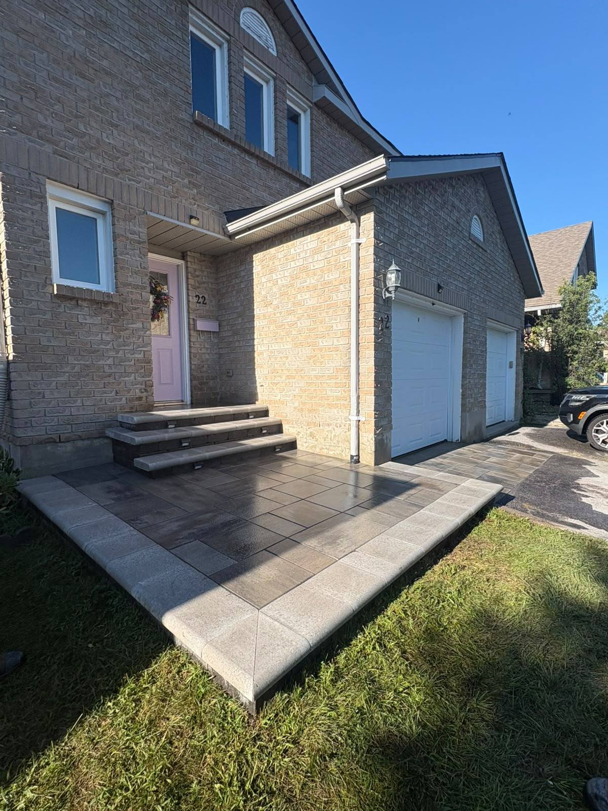 Interlock front entrance with grey large-format pavers, a contrasting border and matching stone steps at a Kingston, Ontario home