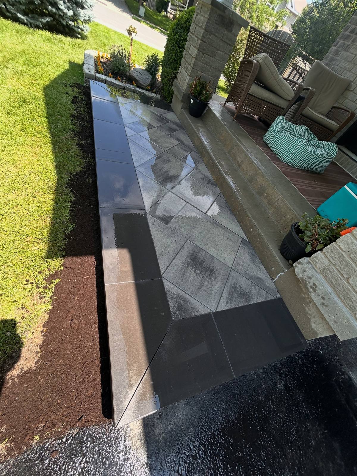 Charcoal bluestone patio landing with black soldier-course border by Gonzo Construction, Kingston area